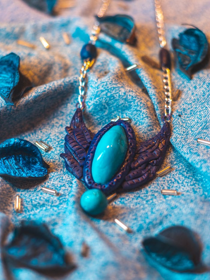 Close-up of a handcrafted blue stone necklace on textured fabric with clay and beads.